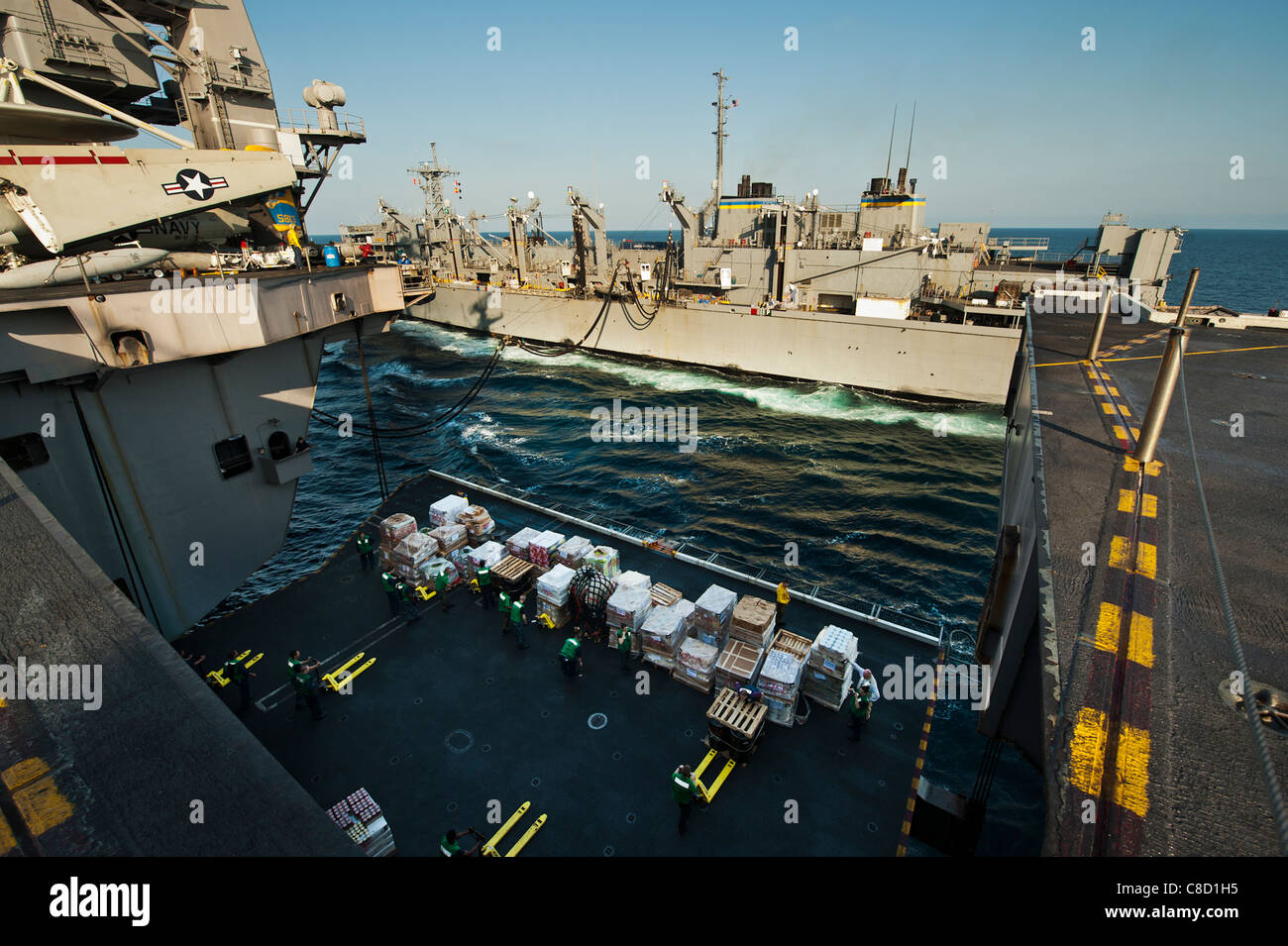 Marinai di rimuovere il carico da un aeromobile ascensore durante un rifornimento verticale a bordo della Nimitz-aeromobili di classe carrier Foto Stock