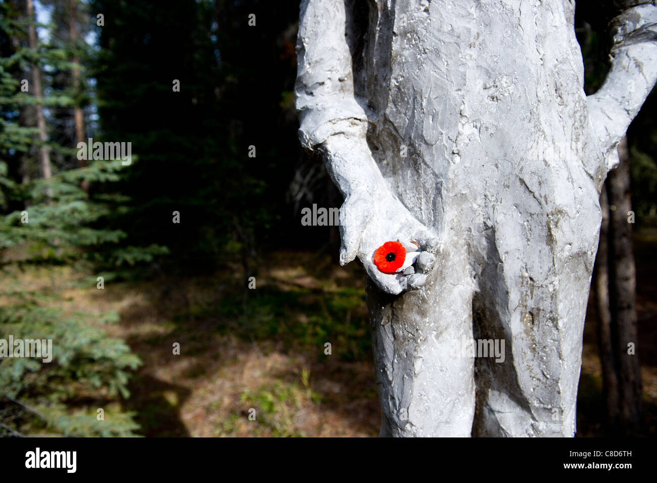 Statua e lapide commemorativa di un uomo circondato da corone colorate in un ambiente forestale presso il Castle Mountain Internment Camp, Banff National Park. Foto Stock