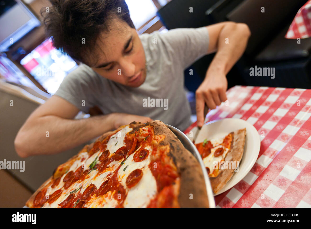 Giovane uomo mangiare la pizza in un ristorante. Foto Stock