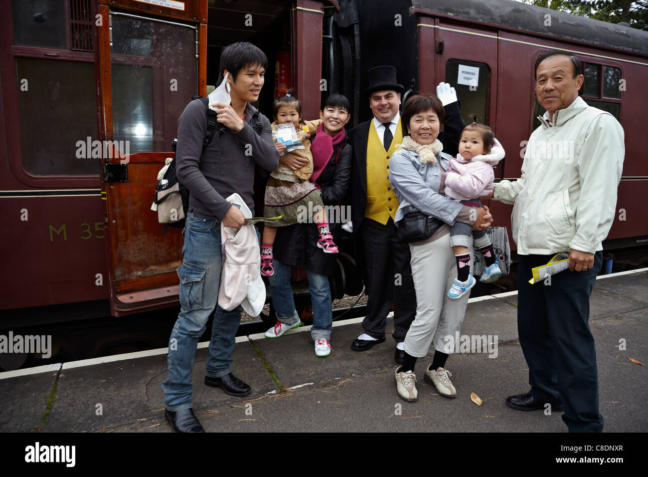Turista giapponese famiglia accolti da Sir Topham Hatt di Thomas Il serbatoio del motore di fama a British stazione ferroviaria prima di salire a bordo. Foto Stock