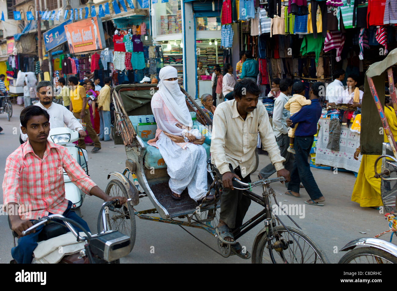 Scena di strada nella città santa di Varanasi, giovane donna musulmana in bianco corse burkha in rickshaw, Benares, India settentrionale Foto Stock