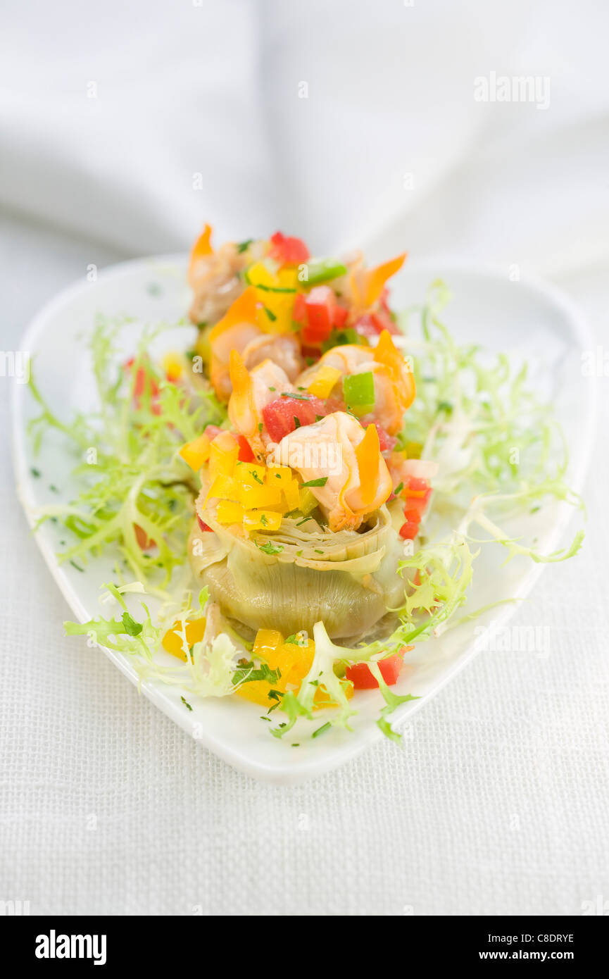 Cuori di carciofi farciti con frutti di mare e tre peperoni colorati Foto Stock