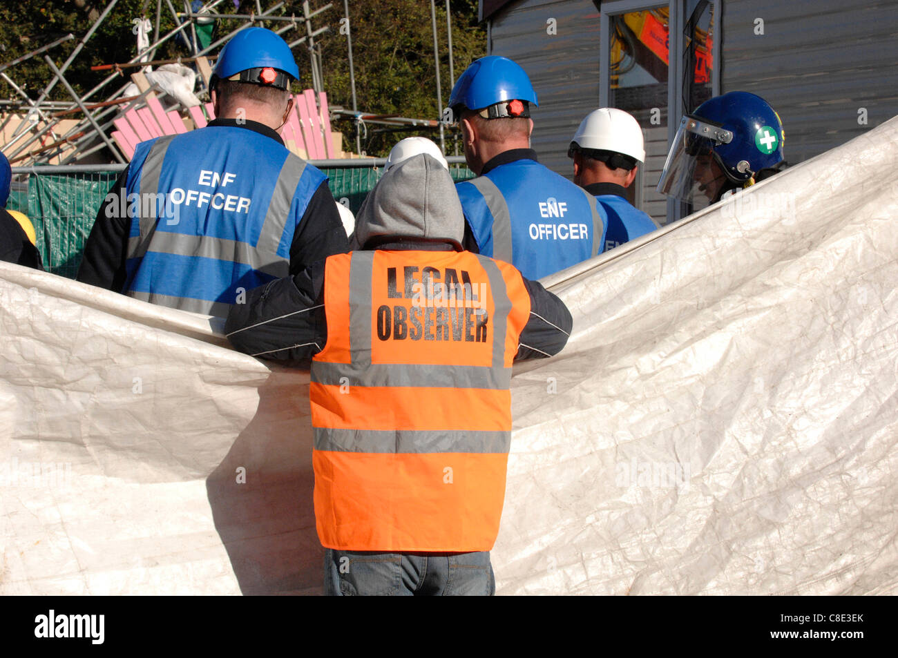 Un osservatore legale tenta invano di guardare due manifestanti essendo extricated dalla canna in cui essi hanno cementato le loro braccia - Bailliffs hanno schermo questa operazione dal punto di vista - lo sfratto prosegue per il secondo giorno di Dale Farm sito viaggiatori Crays Hill, vicino a Basildon, Essex, Regno Unito, Europa. Xx Octo Foto Stock