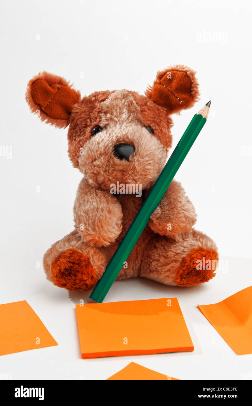 Carino piccolo orsacchiotto con matita su uno sfondo bianco Foto Stock