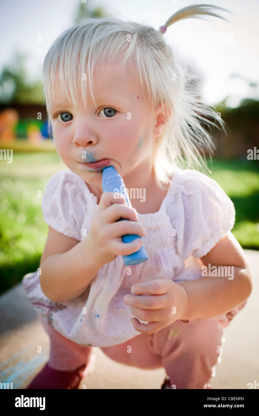 Il Toddler Girl disegno sul suo viso con Sidewalk Chalk Foto Stock