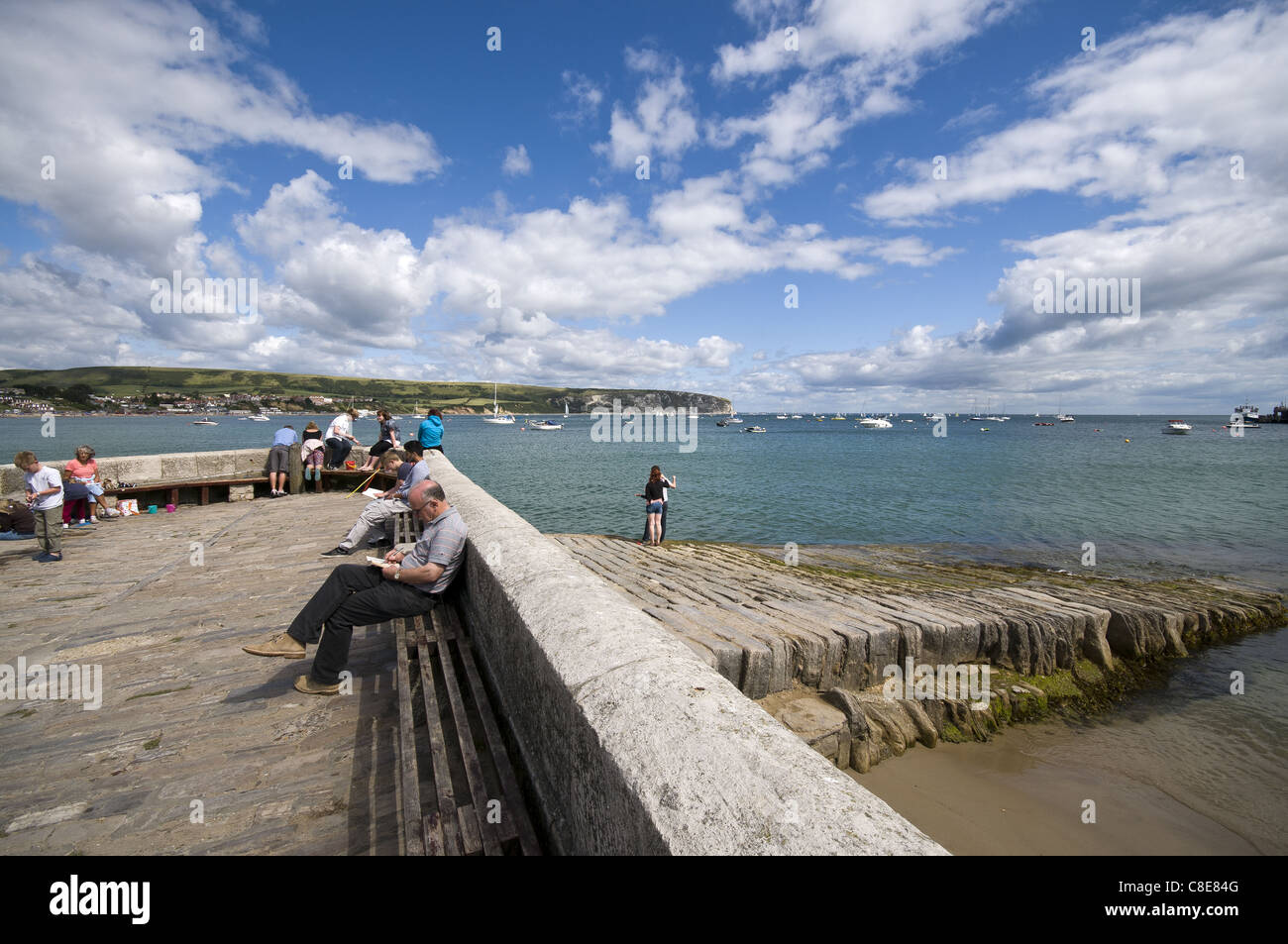 Persone a Swanage Harbour con Ballard punto della distanza, Dorset, England, Regno Unito Foto Stock