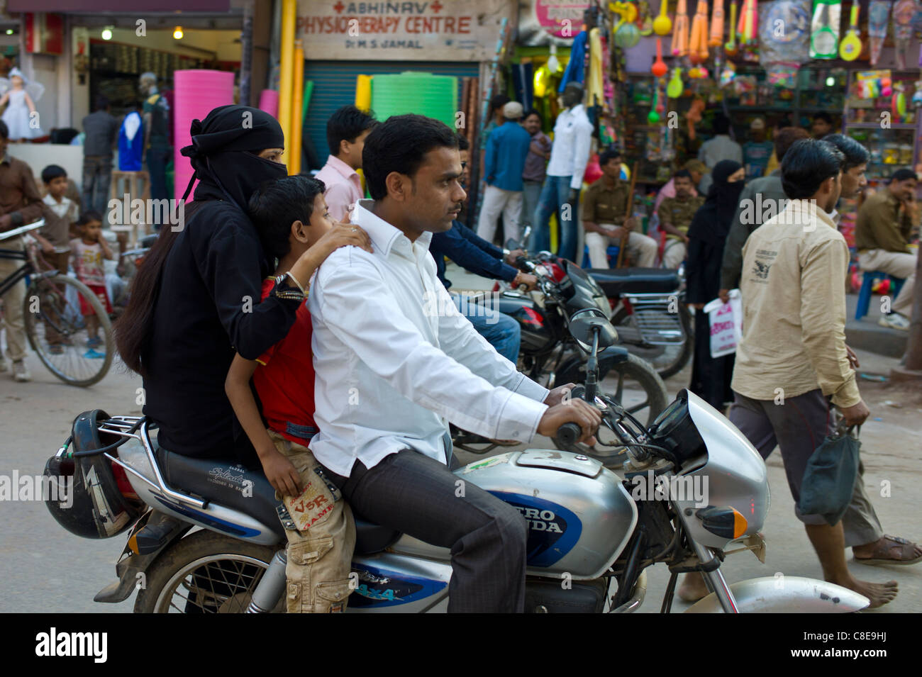 Giovani Musulmani indiani ride famiglia motociclo in scena di strada nella città di Varanasi, Benares, India settentrionale Foto Stock