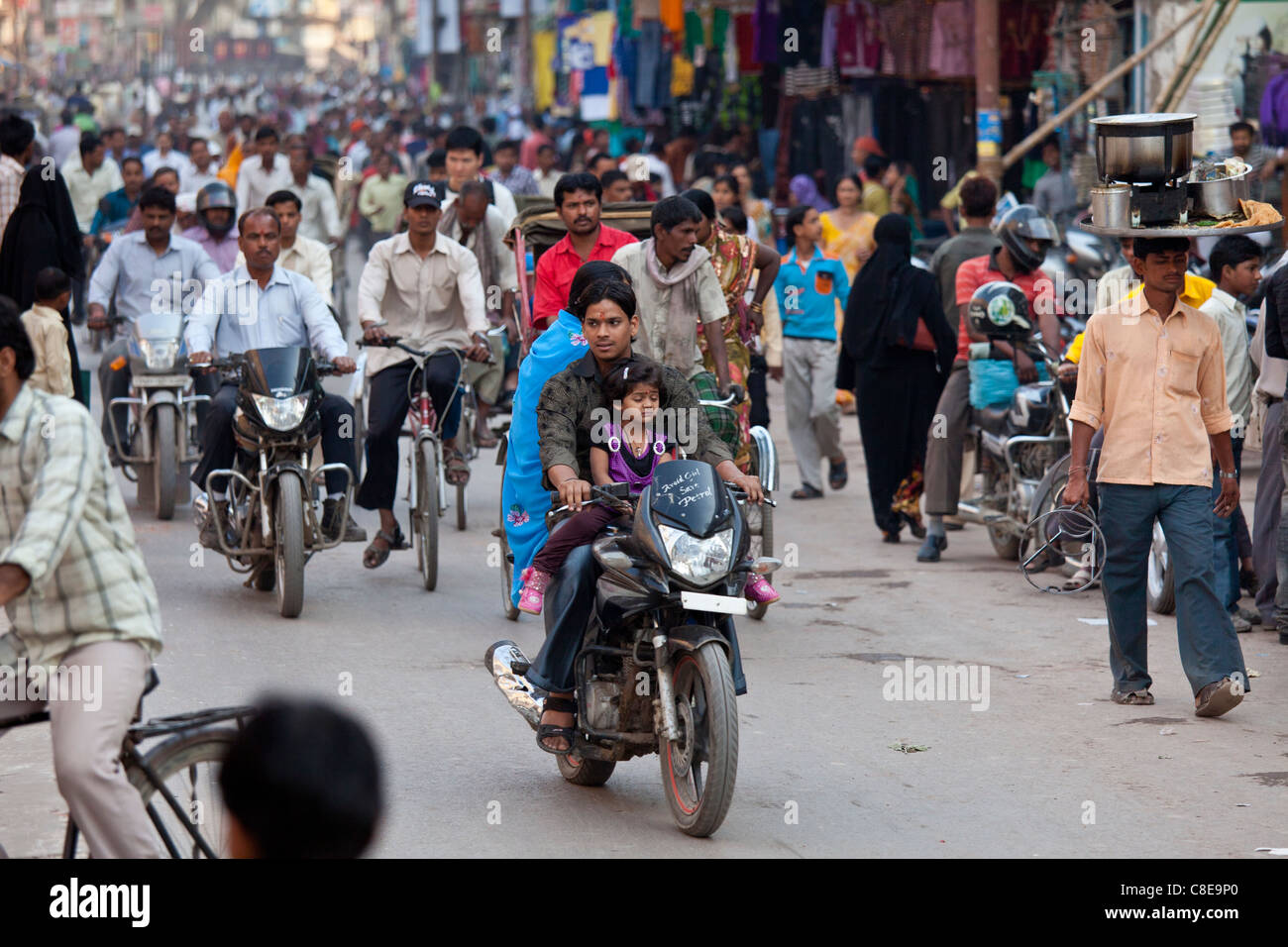 Padre con bambino sul motociclo in strada affollata durante la festa di Shivaratri nella città di Varanasi, India Foto Stock