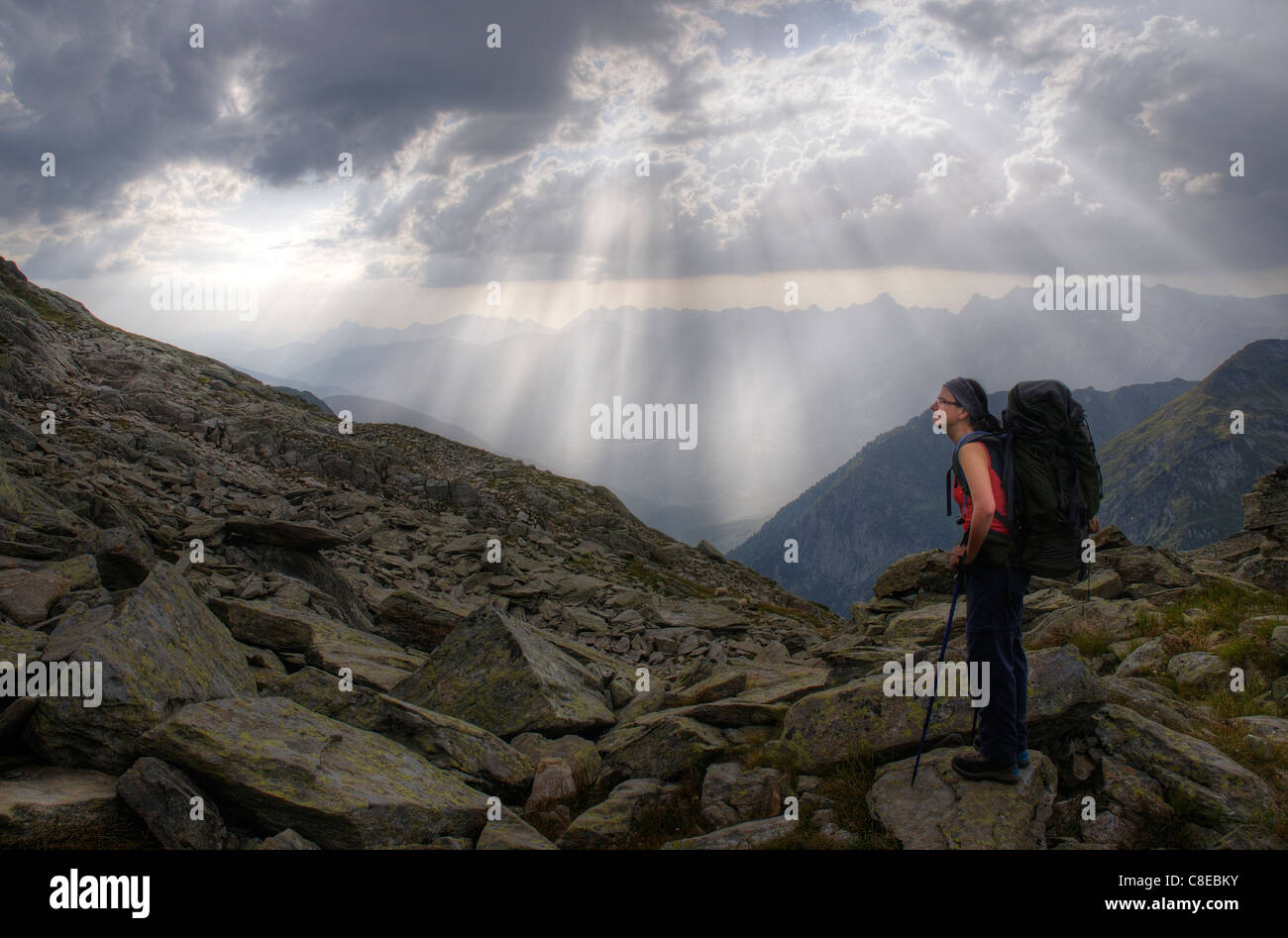 Una montagna di walker pause con drammatica raggi del sole cadere dalle nuvole Foto Stock