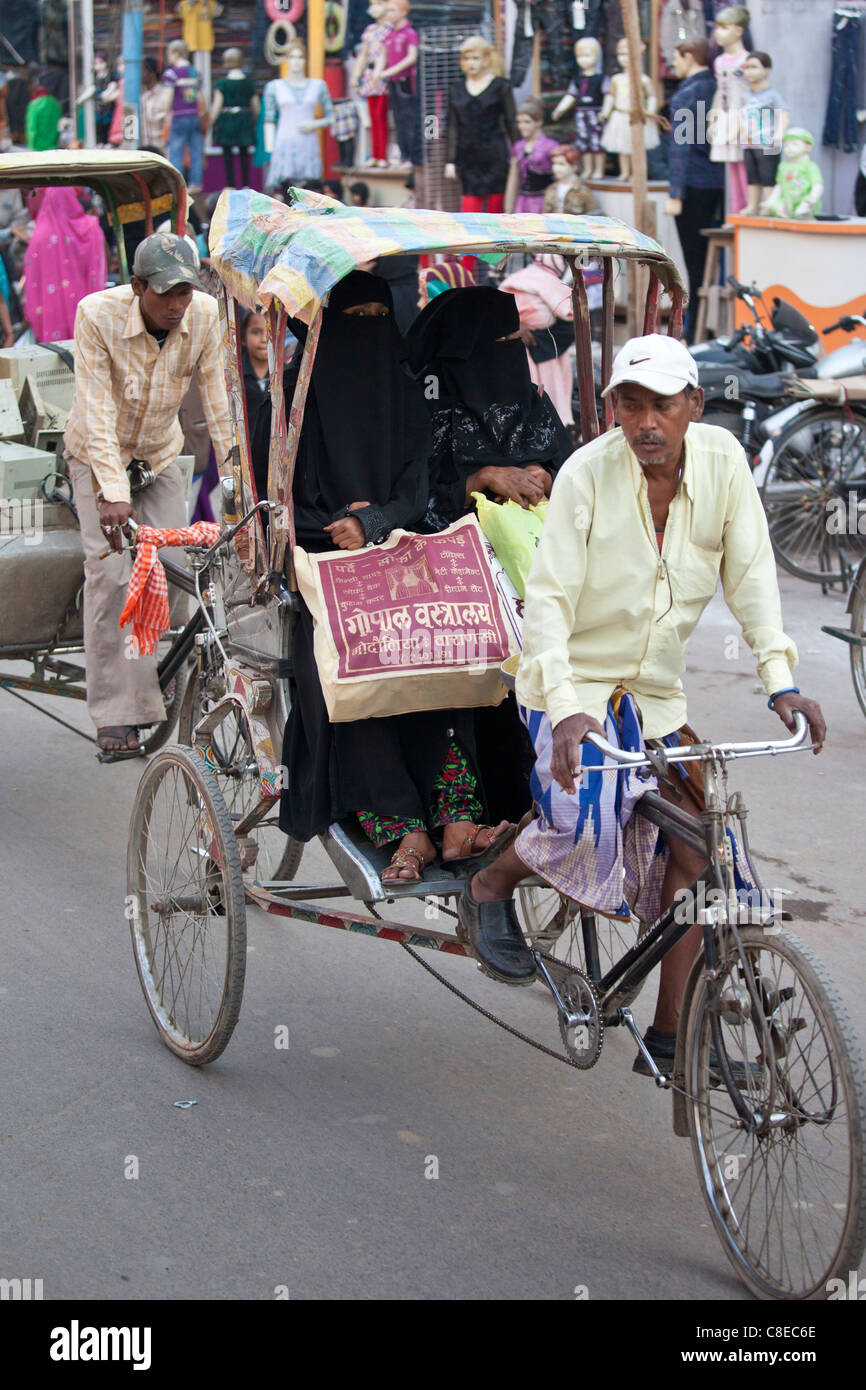 Le donne musulmane corsa in rickshaw in strada affollata scena nella città di Varanasi, Benares, India settentrionale Foto Stock