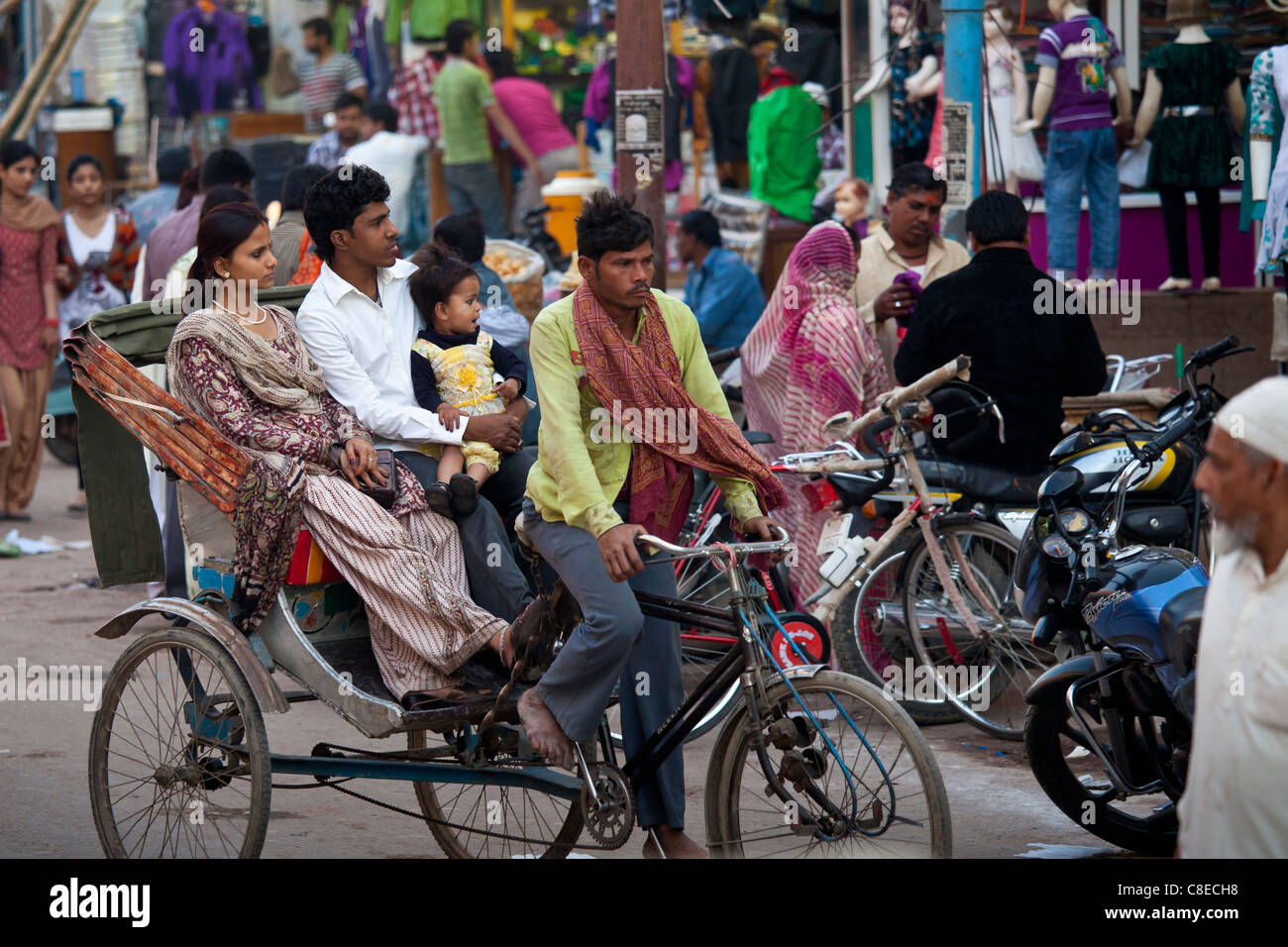 Giovani indiani viaggio di famiglia in rickshaw in strada affollata scena nella città di Varanasi, Benares, India settentrionale Foto Stock