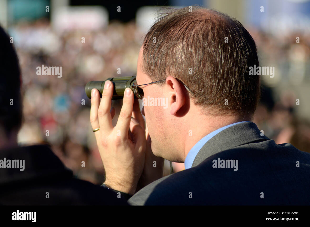 Uomo che utilizza un binocolo per guardare corse ippiche Ascot UK Foto Stock