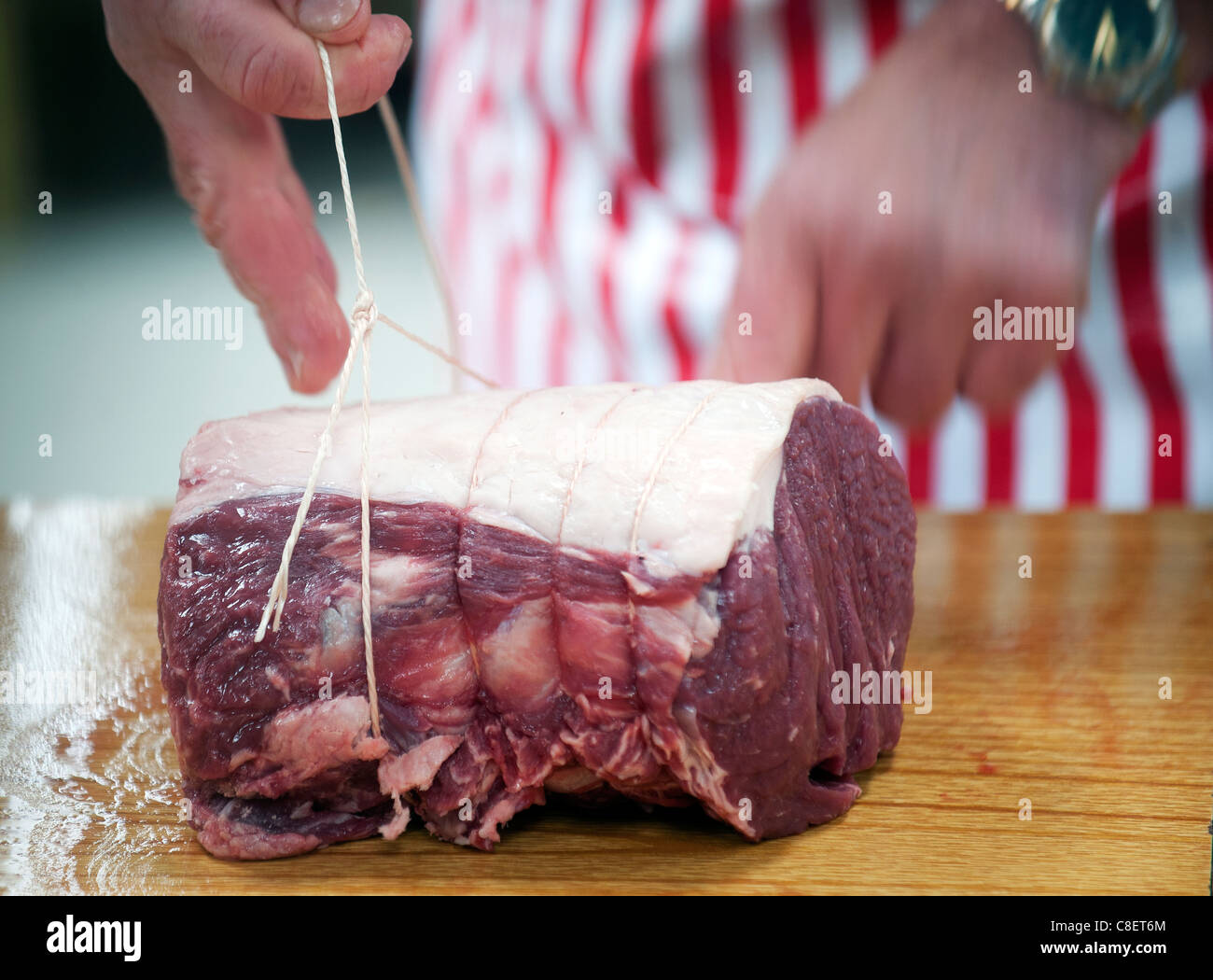 Un macellaio taglia un misto di carni disossate di carni bovine. Foto Stock