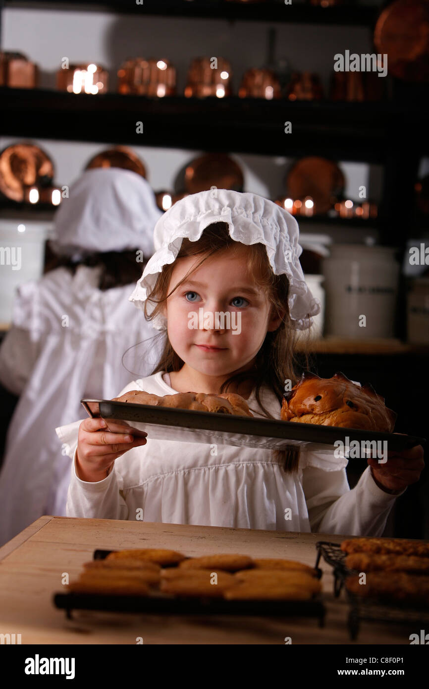Una giovane ragazza vestita in costume vittoriano contiene un vassoio di pane Foto Stock