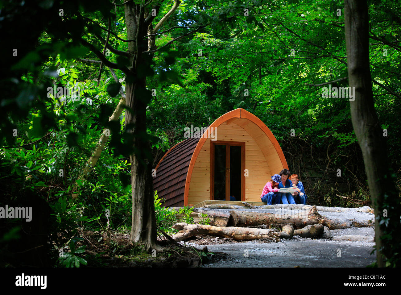 Una famiglia campeggio in una capanna in legno (POD)legge una mappa in un'area in legno Foto Stock