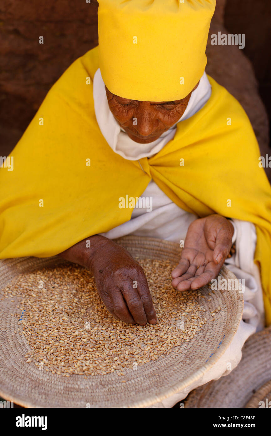 Nun ordinamento di frumento in Bet Maryam chiesa cortile, Lalibela, Wollo, Etiopia Foto Stock
