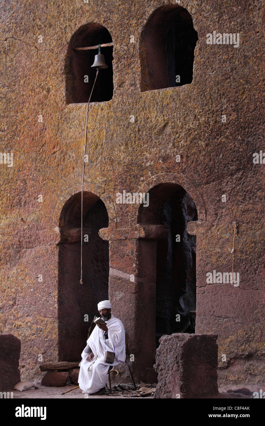 Sacerdote la lettura di una Bibbia in Bet Maryam cortile della chiesa, patrimonio mondiale dell UNESCO, Lalibela, Wollo, Etiopia Foto Stock