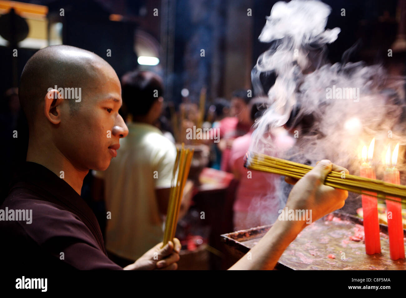 Illuminazione monaco joss bastoni durante una cerimonia in un tempio buddista, Ho Chi Minh City, Vietnam, Indocina, sud-est asiatico Foto Stock