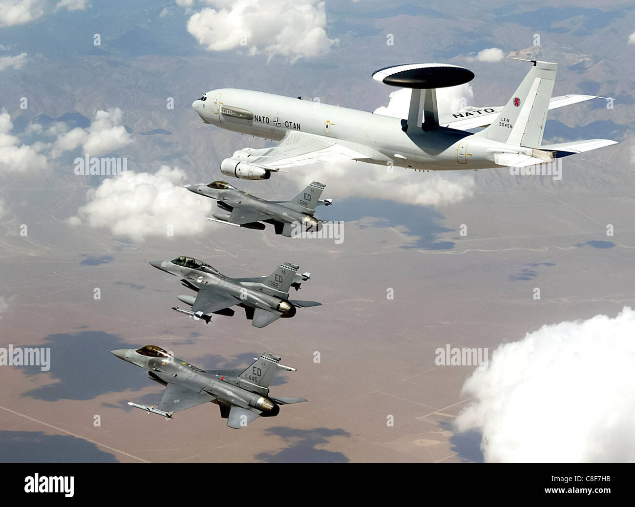 Una NATO E-3 Sentry Airborne Warning e sistema di controllo aereo vola con tre F-16 Fighting Falcon Foto Stock