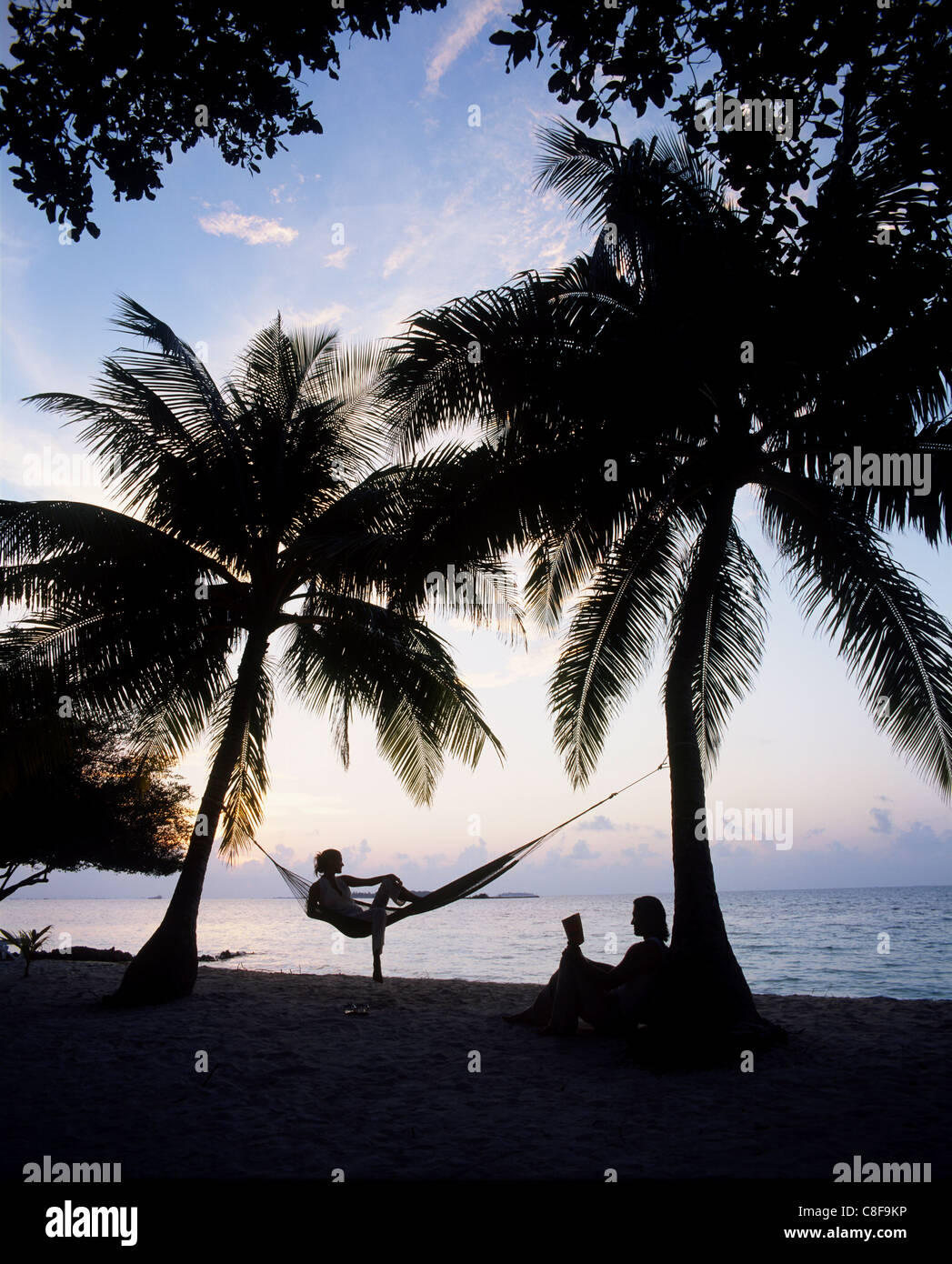Giovane relax su una spiaggia al tramonto, Maldive, Oceano Indiano Foto Stock
