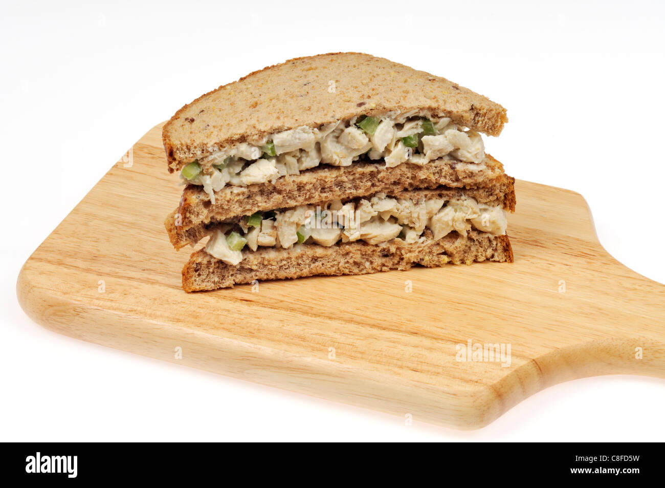 Insalata di pollo in sandwich di pane integrale impilati sul taglio del legno di bordo su sfondo bianco. Foto Stock