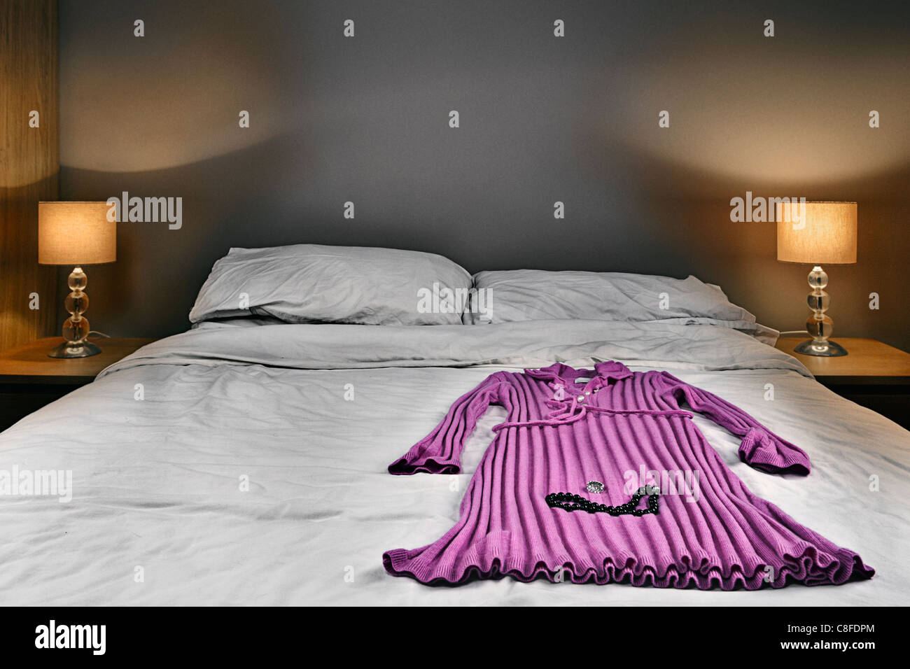 Onorevoli abito rosa e articoli di gioielleria sul letto Foto Stock