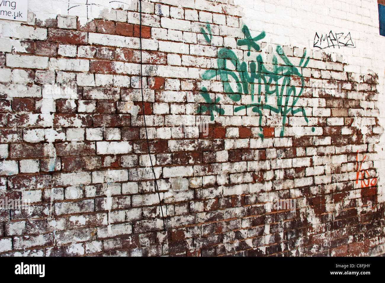 Un weathered muro di mattoni vicino al centro della città, con i tag graffiti Foto Stock