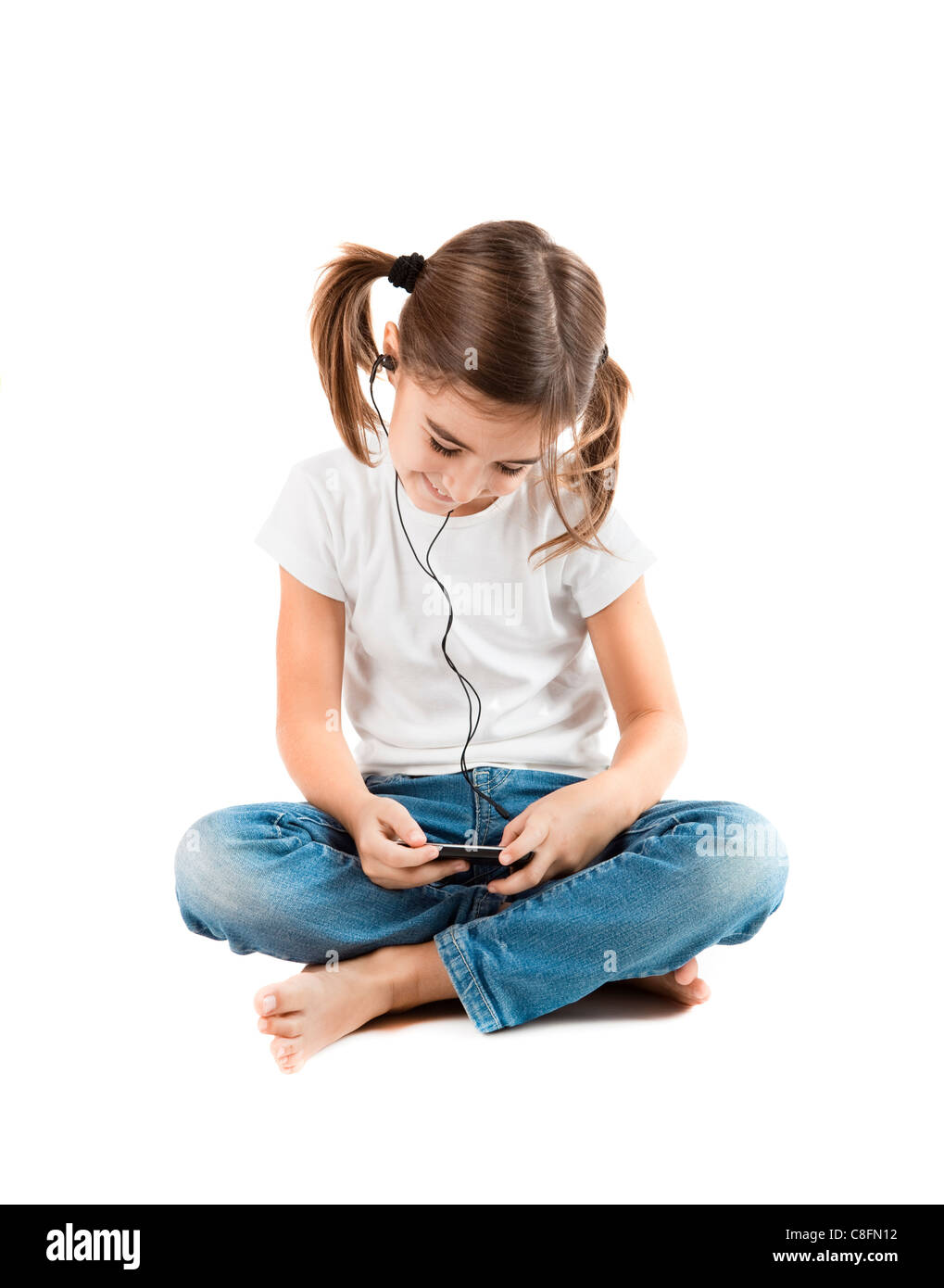 Poco ragazza seduta sul pavimento ascoltare musica con un lettore MP3 Foto Stock