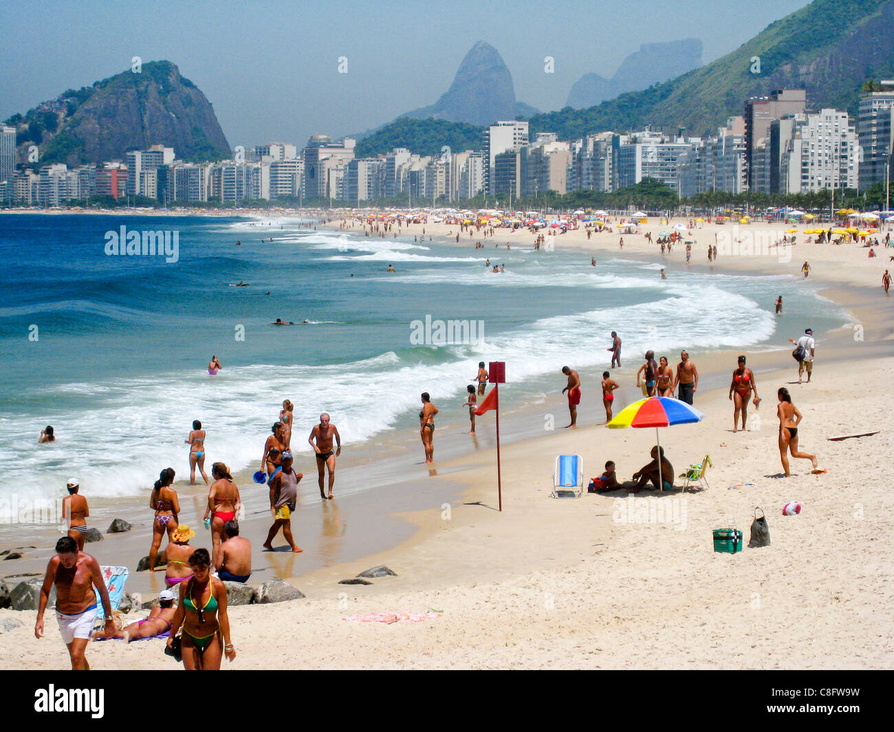 Sulla spiaggia di Copacabana, pieno di bagnanti, lucertole da mare e ombrelloni colorati. Rio de Janeiro, Brasile Foto Stock