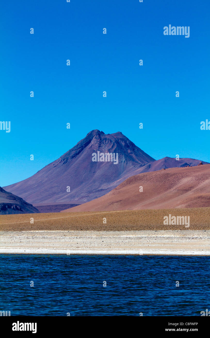 Vulcano soaring dietro Pujsa Salt Lake, il Deserto di Atacama, Cile Foto Stock