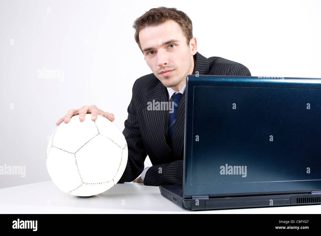 Bello affascinante imprenditore della tuta con sfera di sognare pensando di calcio in prossimità del computer in ufficio Foto Stock