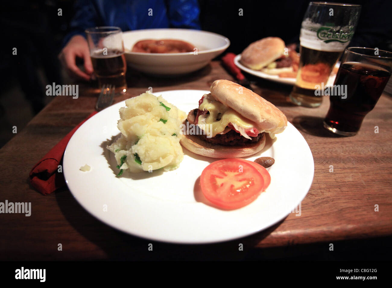 Un cheeseburger servita con champ (purea di patate con lo scalogno) è servita con la birra in un pub. Foto Stock