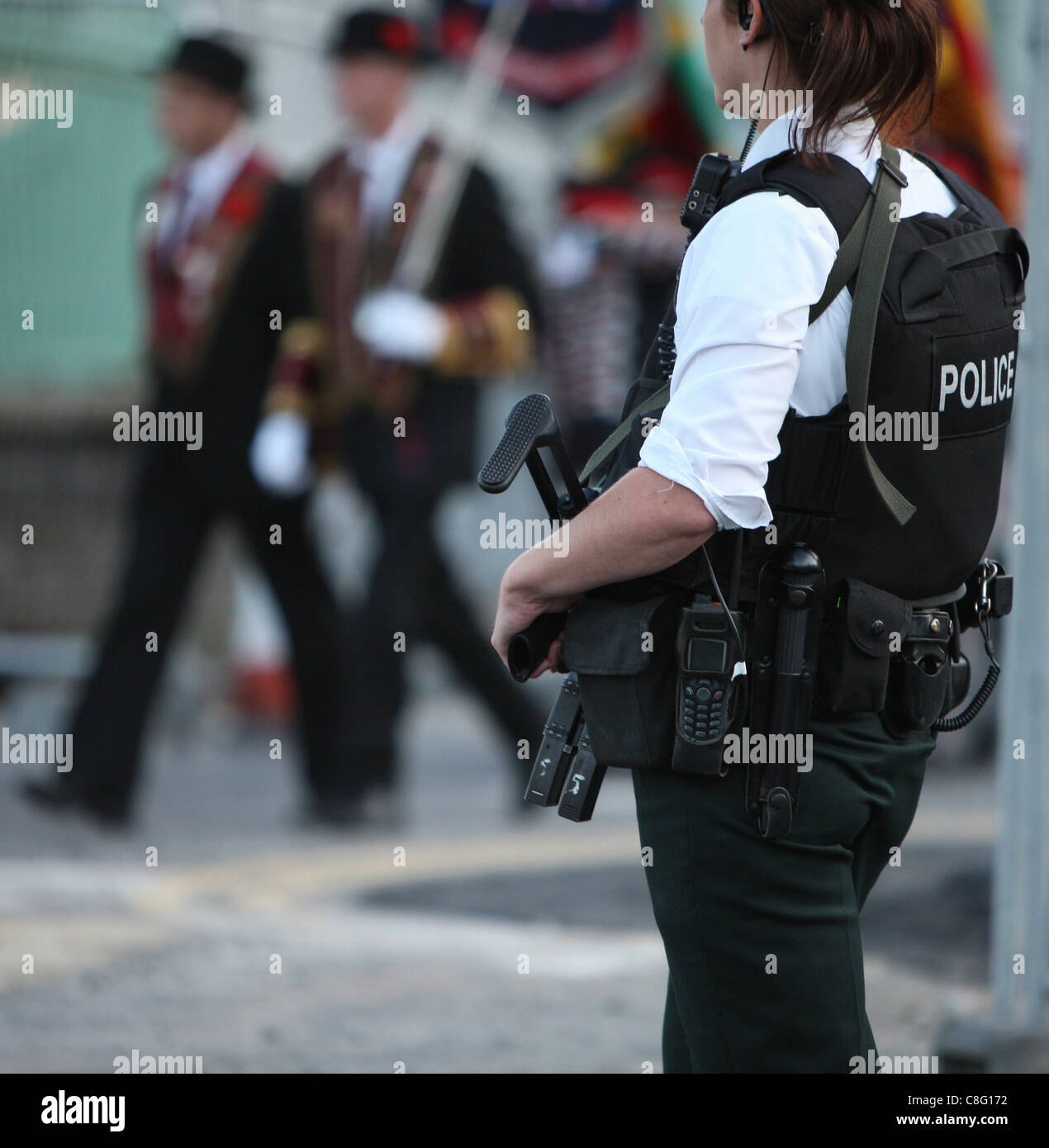 Un funzionario di polizia veglia su di una parata come ella porta una pistola. Foto Stock