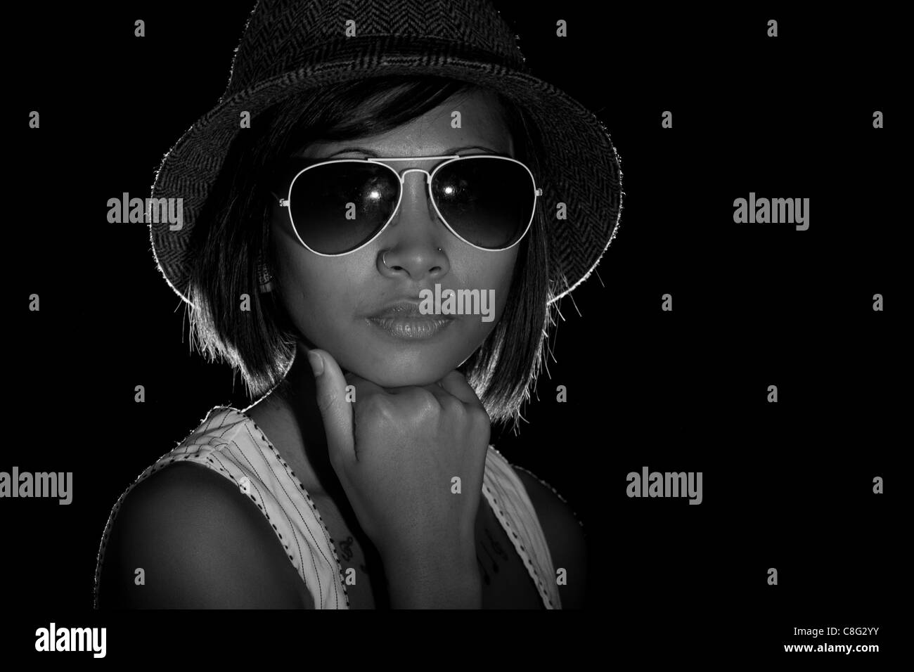 Una immagine in bianco e nero di un bellissimo modello indossando occhiali da sole e cappello. L'immagine è in bianco e nero. Foto Stock