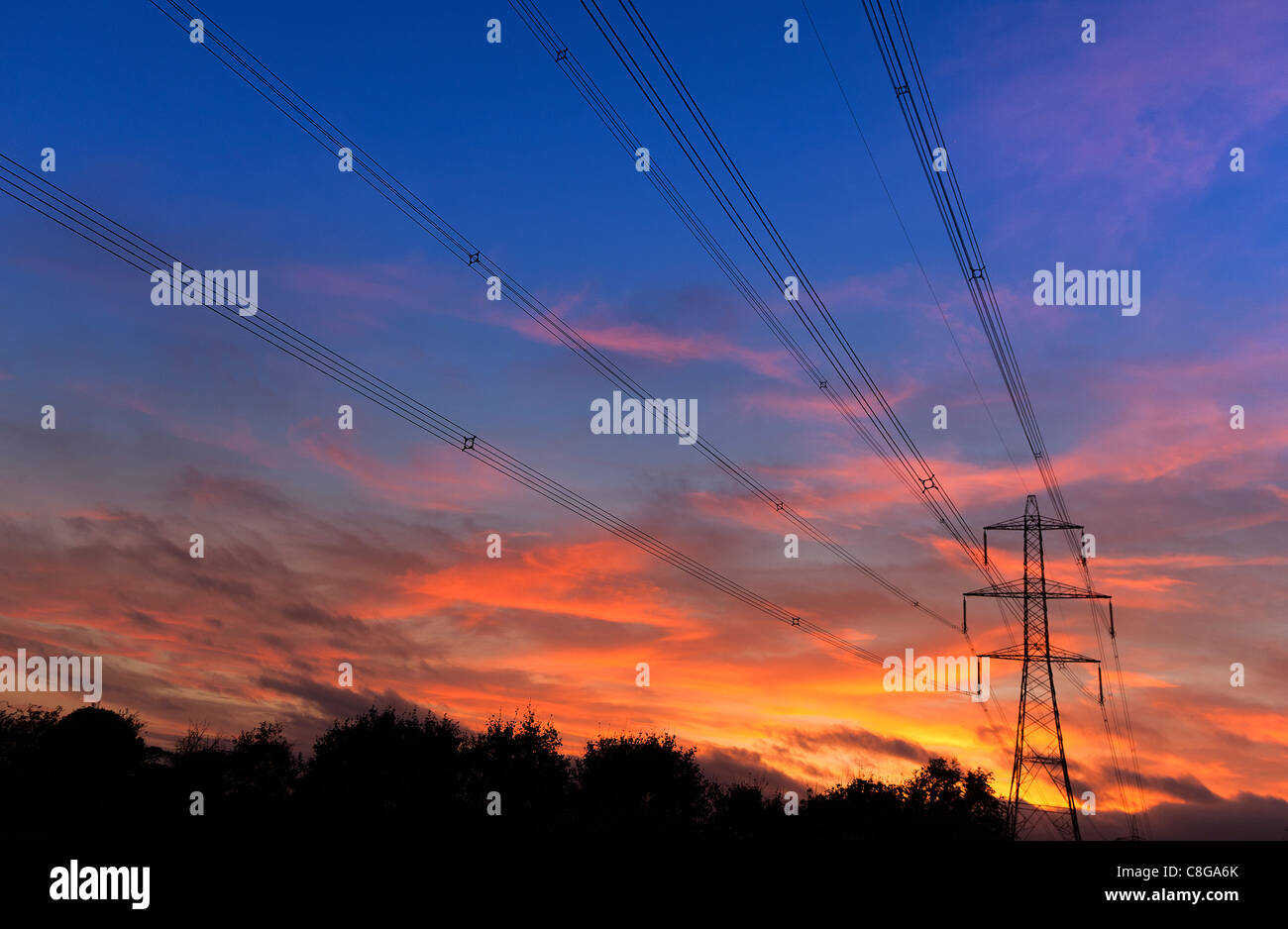 Regno Unito pilone all'alba o al crepuscolo portando ad alta tensione elettrica dei cavi di alimentazione Foto Stock