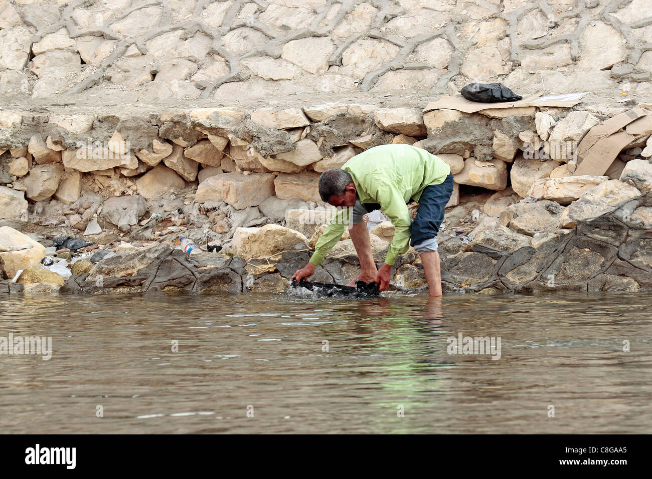 L'uomo il lavaggio della biancheria sulla banca del fiume Nilo al Cairo Foto Stock