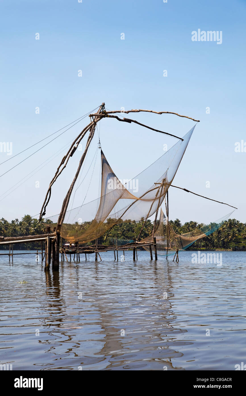 Ritratto reti da pesca in Kerala backwaters laghi, raccolto verticale spazio spazio copia blue sky riflessioni sulla superficie dell'acqua Foto Stock