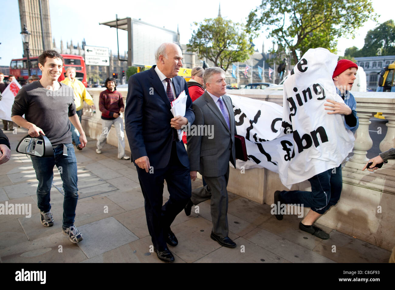 Vince il cavo, il Segretario aziendale, si trova di fronte a manifestanti contrari alla "corporate tax dodging' come egli cammina da Whitehall a Victoria Street, Londra, Regno Unito, lunedì 24 ottobre, 2011. Foto Stock