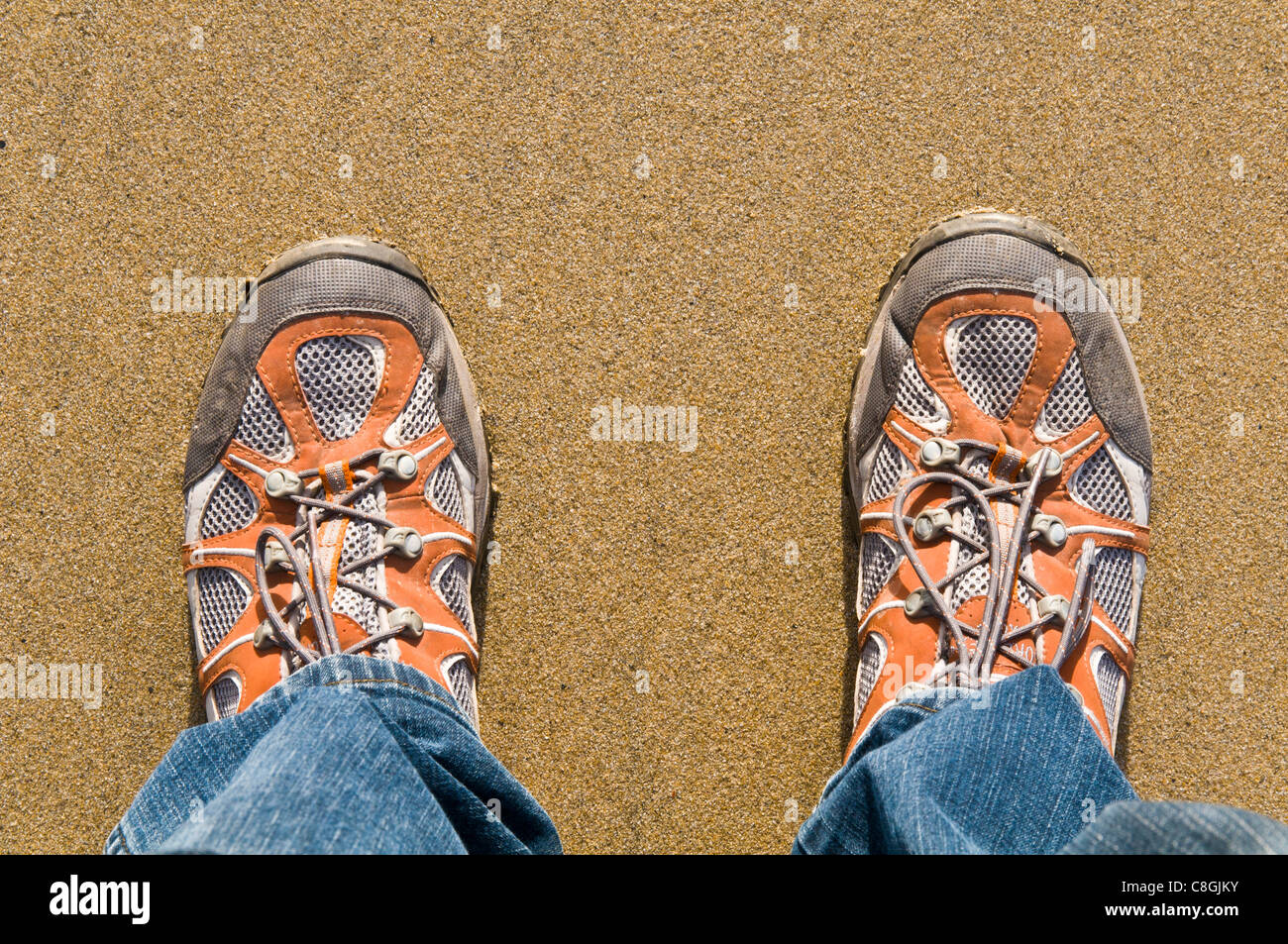 Guardando verso il basso in corrispondenza di una coppia di piedi di mens in scarpe da ginnastica Foto Stock