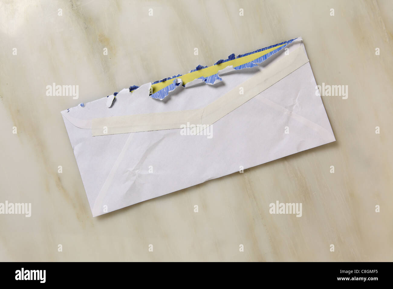 Un usato e leggermente strappata bianco aperto busta postale su un piano di marmo Foto Stock