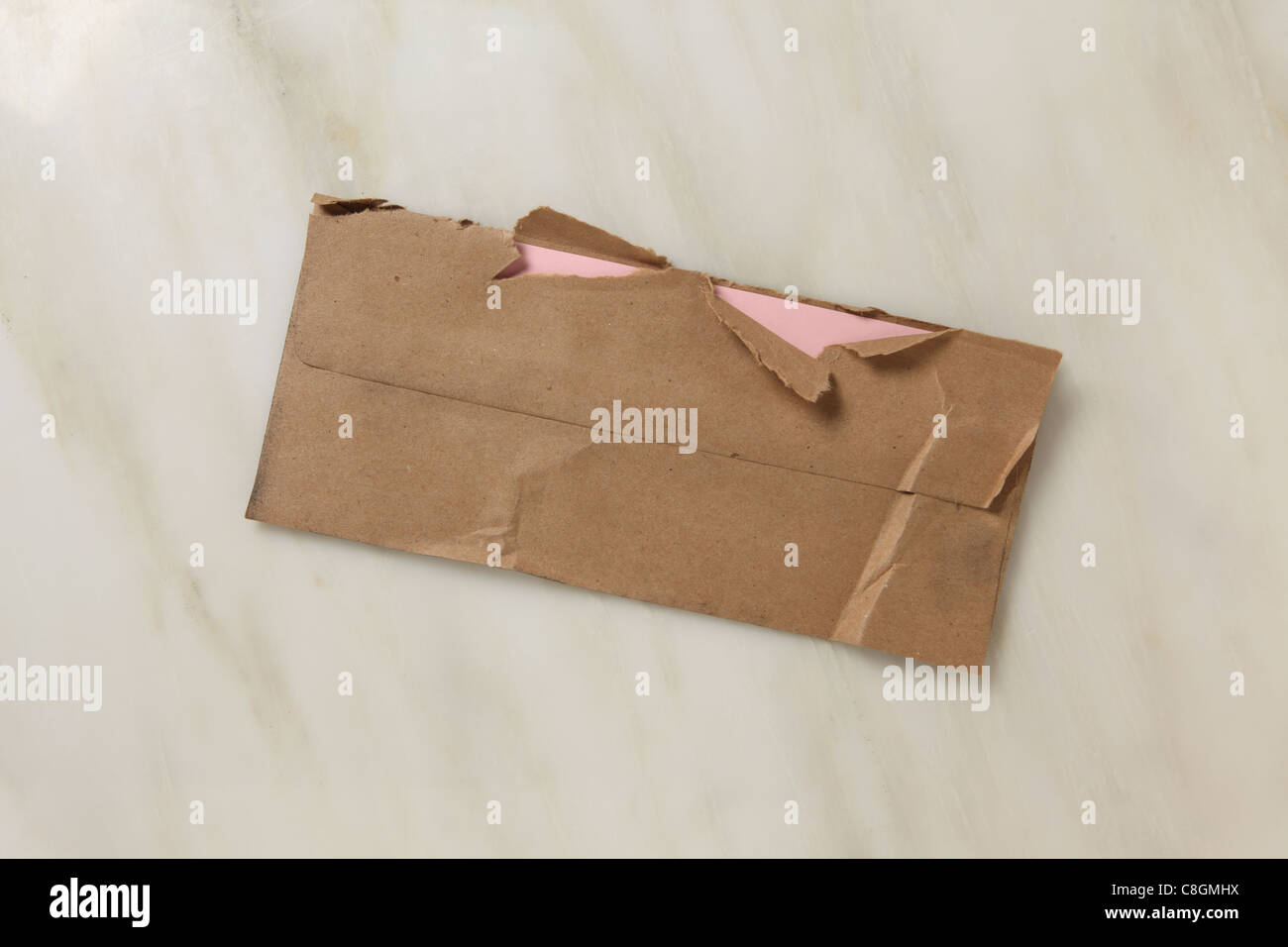 Un usato e leggermente strappata aperta marrone busta postale su un piano di marmo Foto Stock