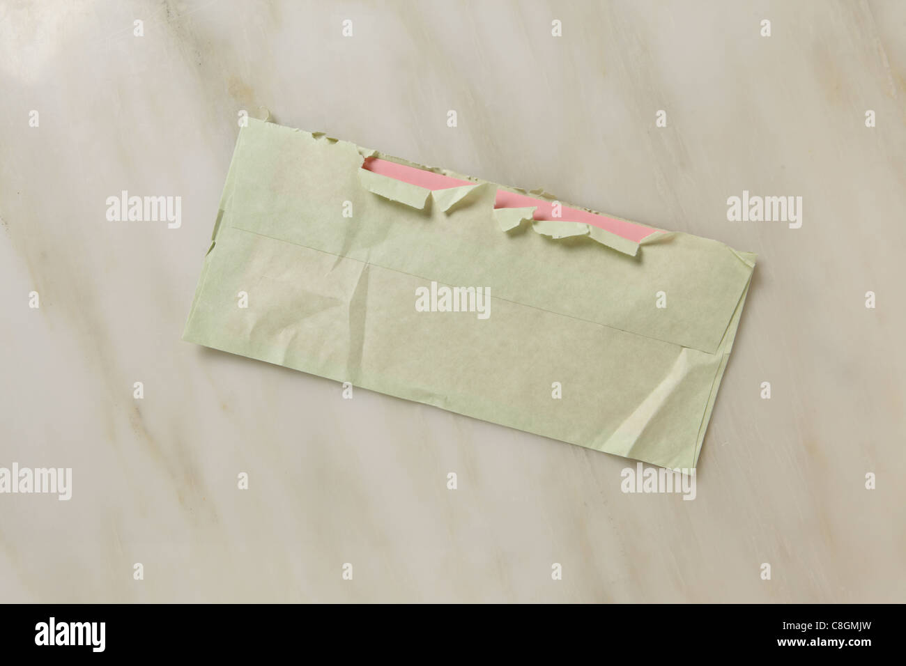 Un usato e leggermente strappato aperto verde busta postale su un piano di marmo Foto Stock