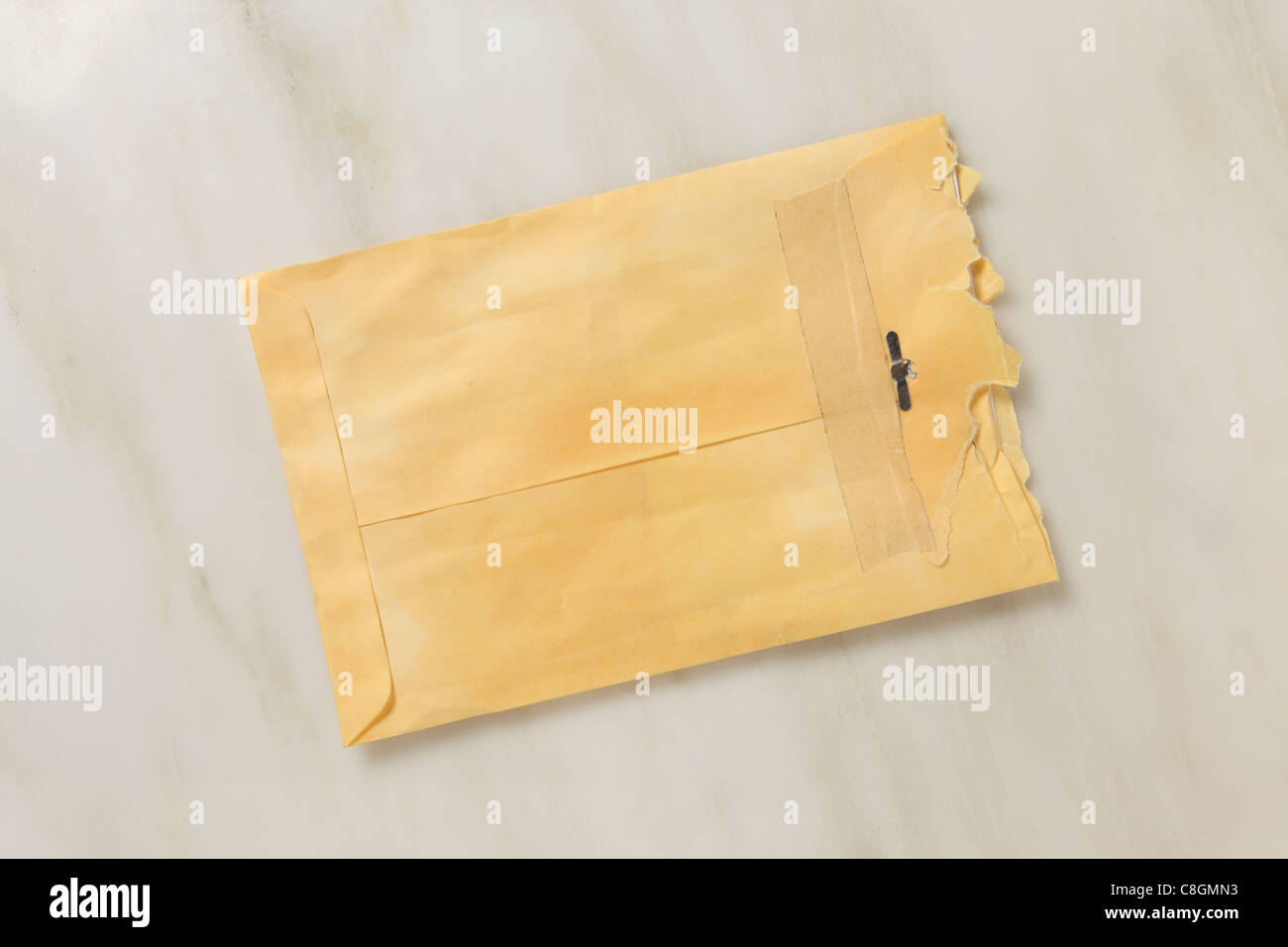 Un usato e leggermente strappato aperto manilla colorato busta postale su un piano di marmo Foto Stock