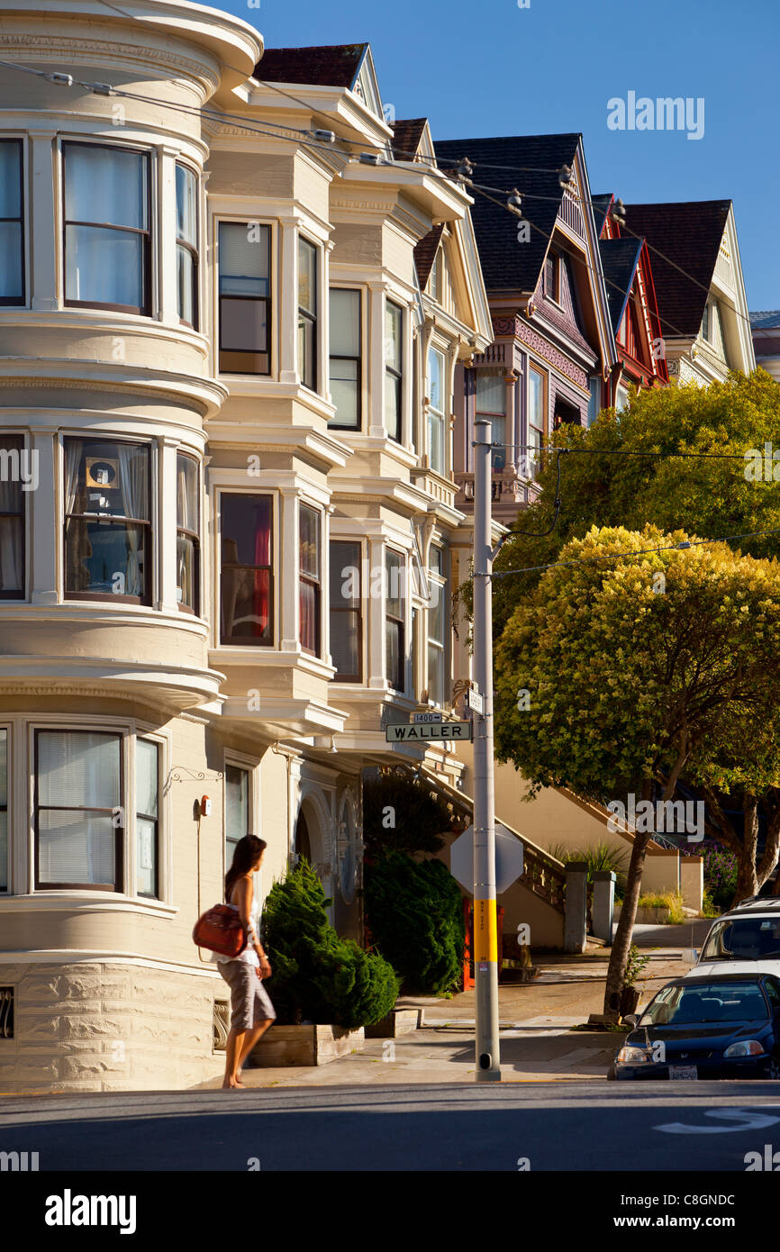 Le donne camminano davanti alle case in stile vittoriano nel quartiere Haight Ashbury di San Francisco, California, USA Foto Stock