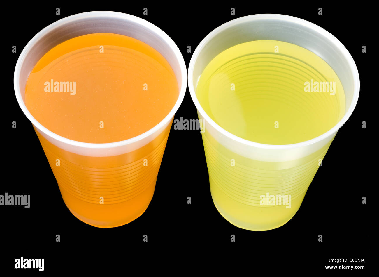 Due bicchieri di plastica di colore giallo e con liquido arancione. Foto Stock
