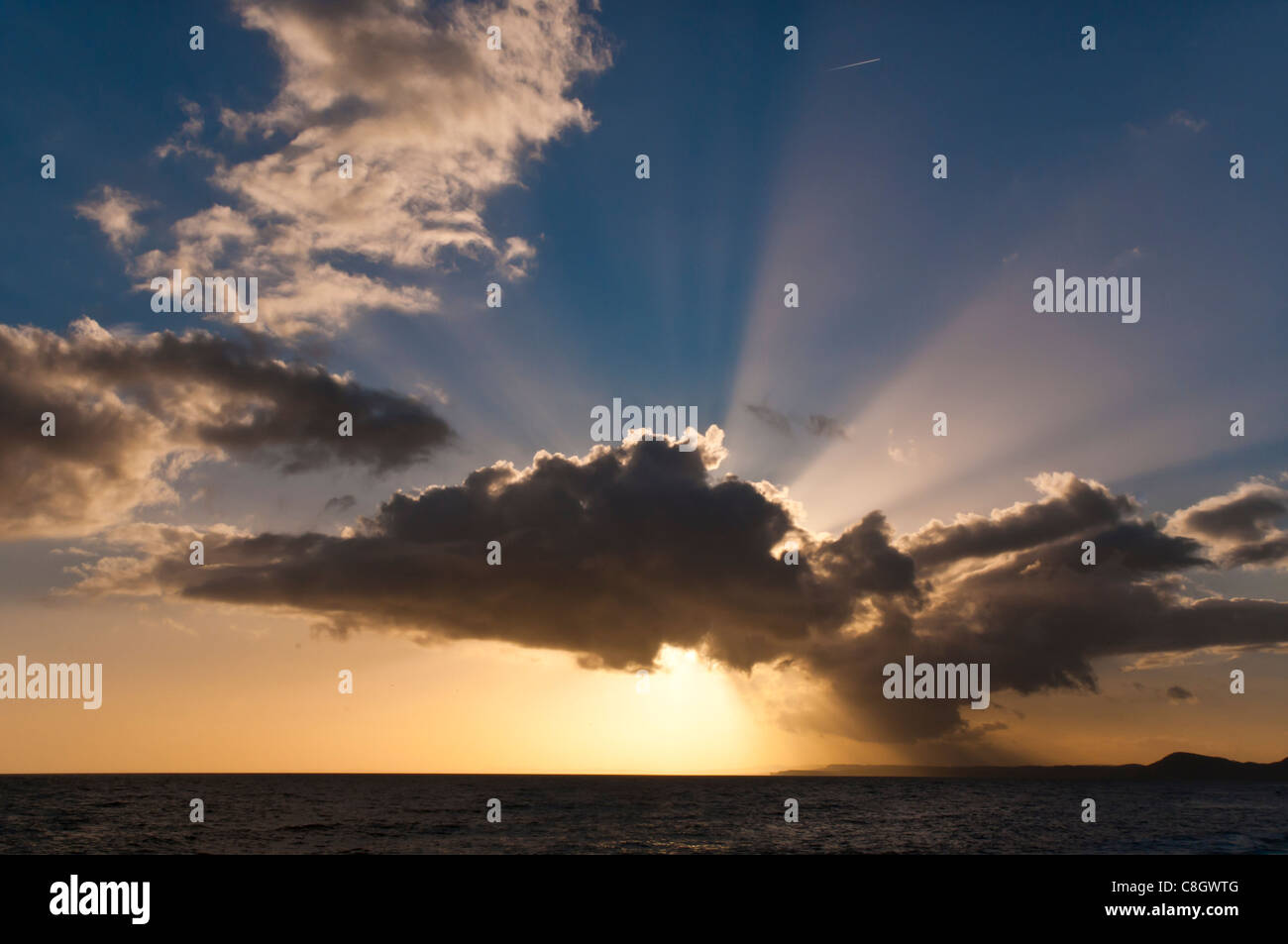 Nuvole drammatico e impostazione di sole sulla spiaggia di Devon Foto Stock