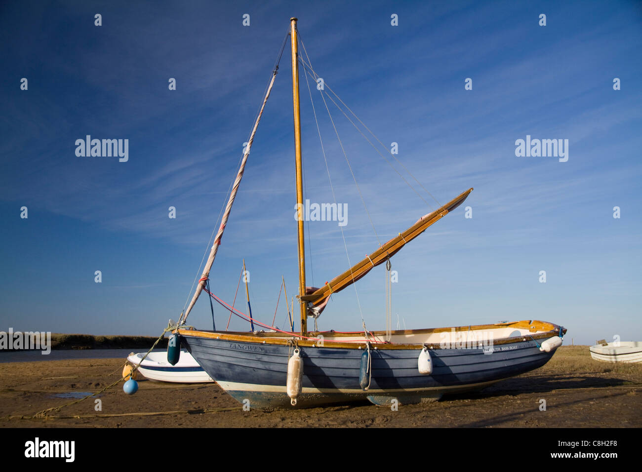 Una piccola barca a vela si trova nel fango sull'Agar Creek off il canale Blakeney a Blakeney in Suffolk Foto Stock