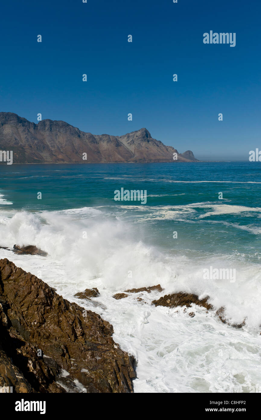 La frantumazione delle onde sui massi lungo il percorso 44 False Bay Western Cape Sud Africa Foto Stock