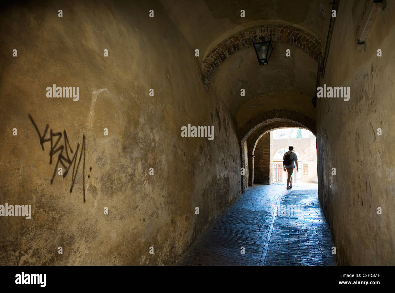 Un backpacker passeggiate attraverso un tunnel con graffiti, Siena, Italia Foto Stock