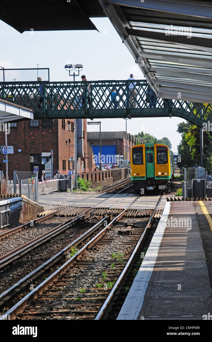 Treno in avvicinamento a Chichester stazione ferroviaria circa per andare oltre il passaggio a livello. Foto Stock